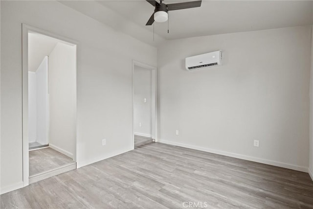 interior space with a wall mounted AC, lofted ceiling, baseboards, and wood finished floors