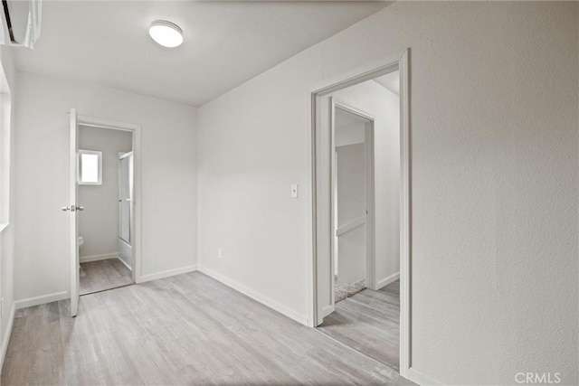 unfurnished bedroom with baseboards, connected bathroom, and wood finished floors