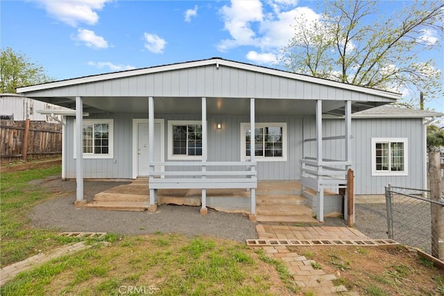 back of house featuring a porch, board and batten siding, and fence