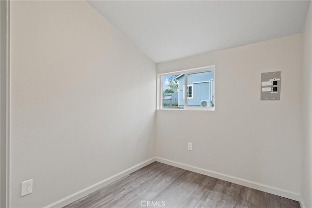 unfurnished room featuring baseboards, vaulted ceiling, and wood finished floors