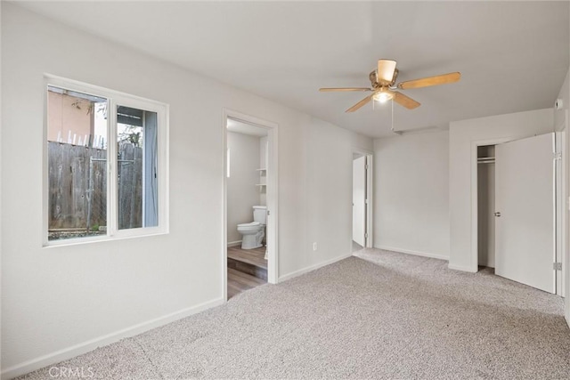 unfurnished bedroom with a closet, baseboards, ensuite bathroom, ceiling fan, and carpet flooring