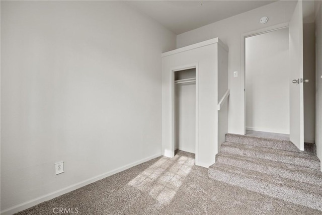 unfurnished bedroom featuring carpet floors, baseboards, and a closet