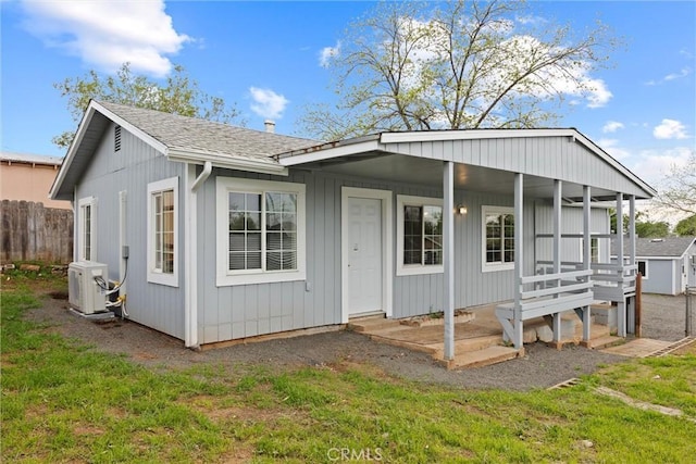rear view of property with ac unit, a porch, fence, and a shingled roof