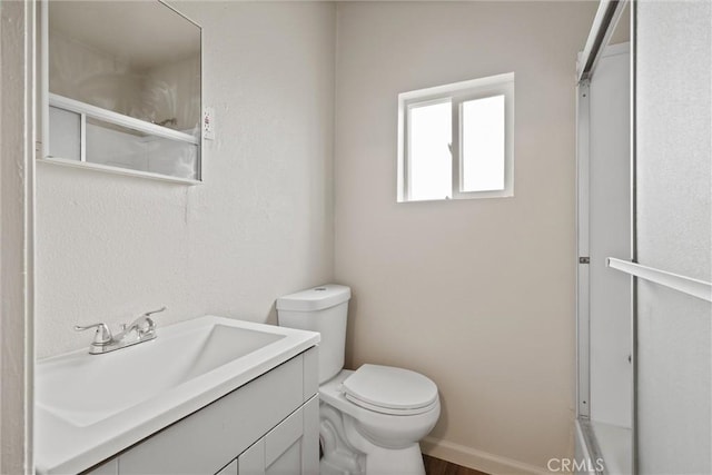 bathroom featuring a shower, vanity, baseboards, and toilet