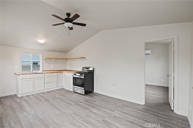 kitchen with light wood-style floors, stainless steel range with gas stovetop, a ceiling fan, open shelves, and vaulted ceiling