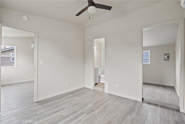 unfurnished bedroom featuring multiple windows, baseboards, and light wood finished floors