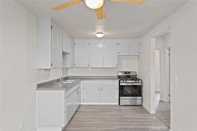 kitchen with a sink, stainless steel range with gas stovetop, a ceiling fan, and light wood finished floors