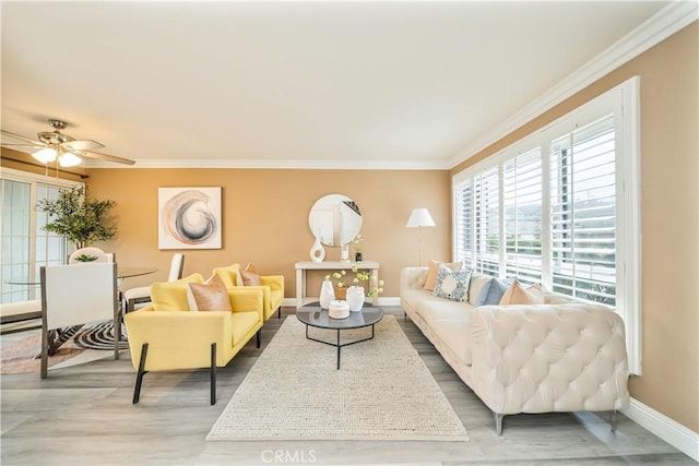 living room with baseboards, crown molding, ceiling fan, a baseboard radiator, and wood finished floors