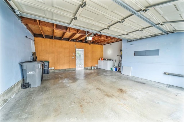 garage with a garage door opener, wooden walls, and washing machine and clothes dryer