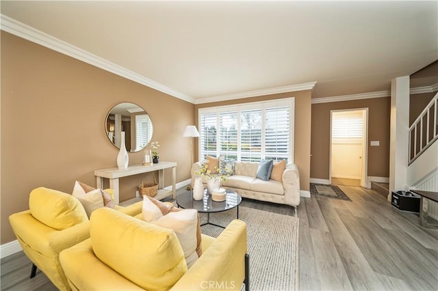 living area featuring crown molding, baseboards, wood finished floors, and stairs
