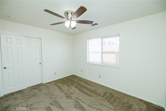 unfurnished bedroom featuring a closet, baseboards, visible vents, ceiling fan, and carpet