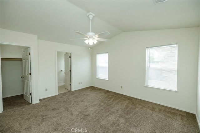 unfurnished bedroom with a closet, baseboards, a spacious closet, carpet flooring, and lofted ceiling
