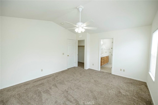 unfurnished bedroom with multiple windows, light colored carpet, vaulted ceiling, and connected bathroom