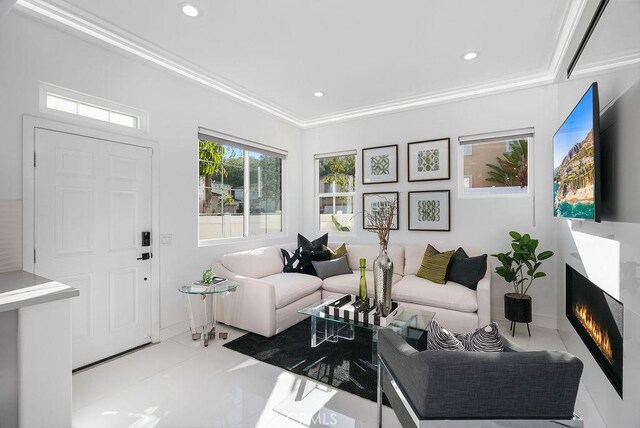 living room with recessed lighting, a warm lit fireplace, crown molding, and baseboards