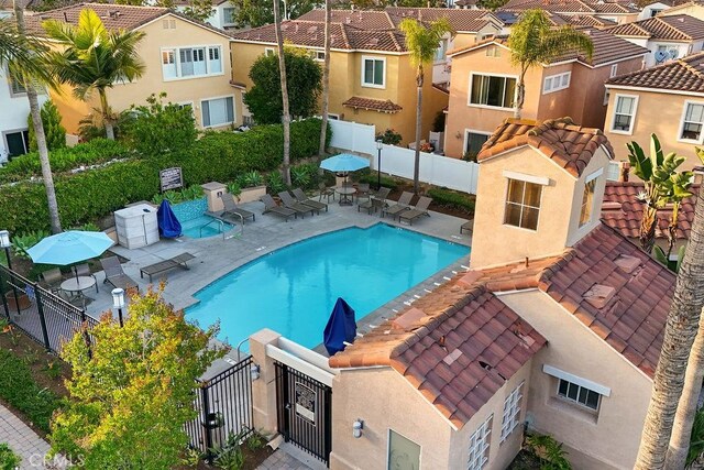 community pool with a residential view, a patio area, and a gate