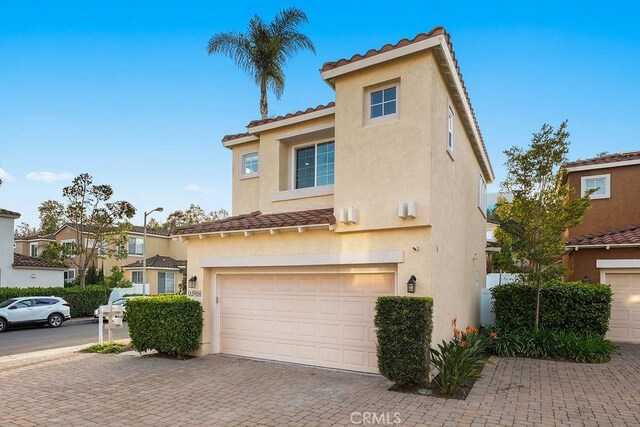 view of front of home featuring a tile roof, stucco siding, a garage, and decorative driveway