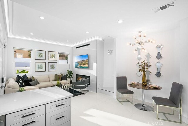 living area with a chandelier, recessed lighting, light tile patterned floors, baseboards, and ornamental molding