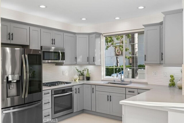 kitchen with stainless steel appliances, gray cabinetry, a sink, and recessed lighting