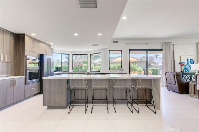 kitchen featuring light countertops, modern cabinets, visible vents, and a breakfast bar