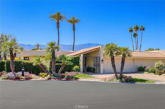 view of front of home with a mountain view, a garage, concrete driveway, a tile roof, and stucco siding