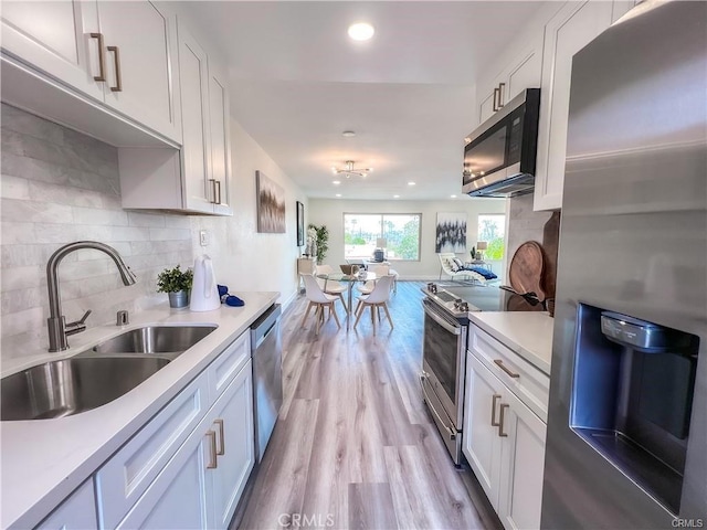 kitchen with recessed lighting, a sink, light wood-type flooring, light countertops, and appliances with stainless steel finishes
