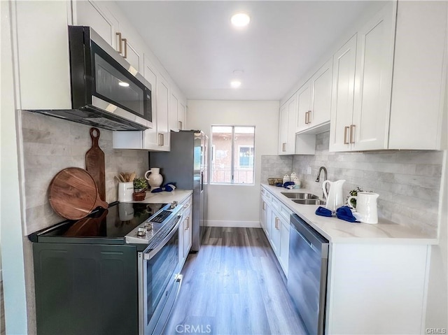 kitchen with tasteful backsplash, light wood-type flooring, stainless steel appliances, and a sink