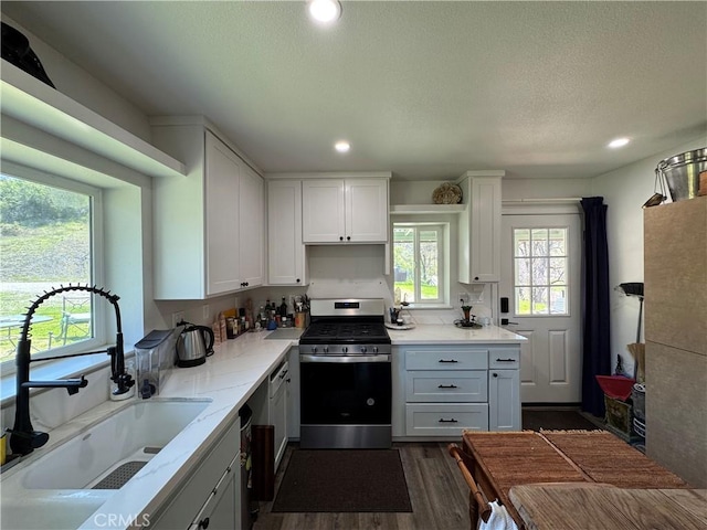 kitchen featuring recessed lighting, gas range, dark wood-style floors, and a sink