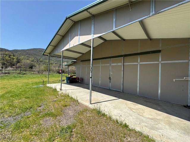 view of side of home with a mountain view and a lawn
