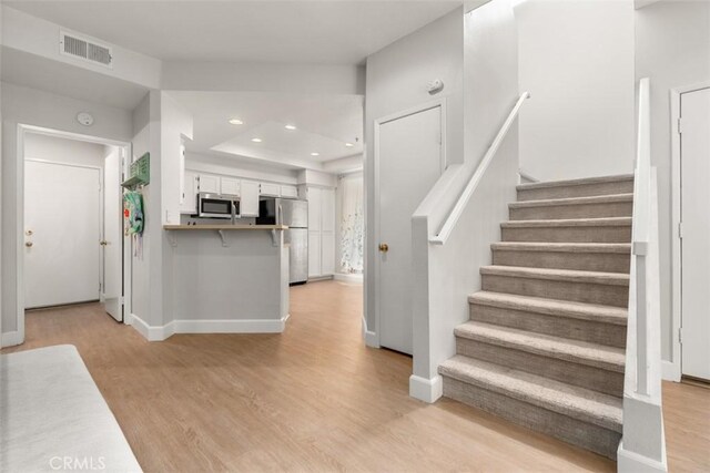 stairs with baseboards, wood finished floors, visible vents, and recessed lighting