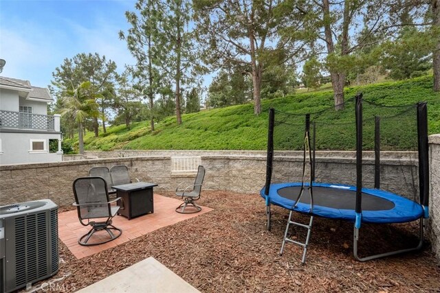 view of yard with a fire pit, a trampoline, central AC, and a patio