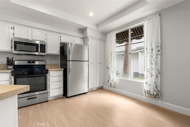 kitchen with light wood finished floors, light countertops, white cabinets, and appliances with stainless steel finishes