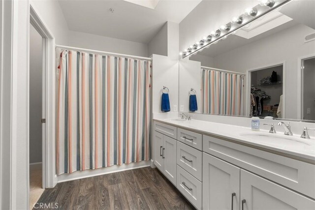 full bathroom featuring double vanity, visible vents, wood finished floors, and a sink