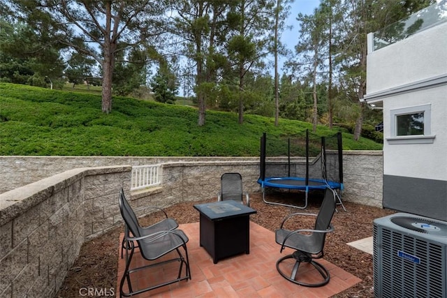 view of patio / terrace with a fire pit, cooling unit, and a trampoline