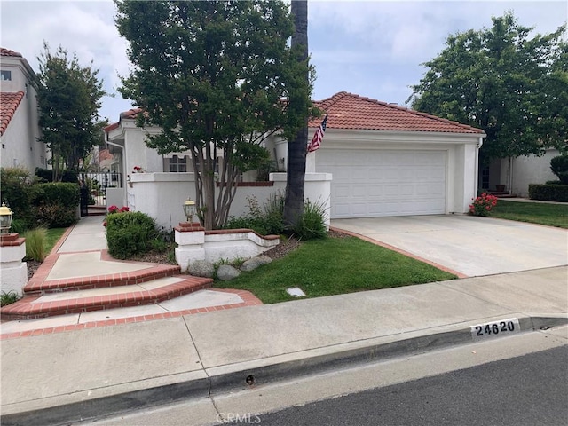 view of front of home with stucco siding, driveway, an attached garage, a tiled roof, and a gate