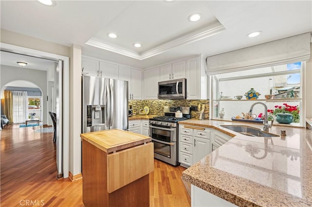 kitchen featuring wood counters, stainless steel appliances, white cabinets, and a sink