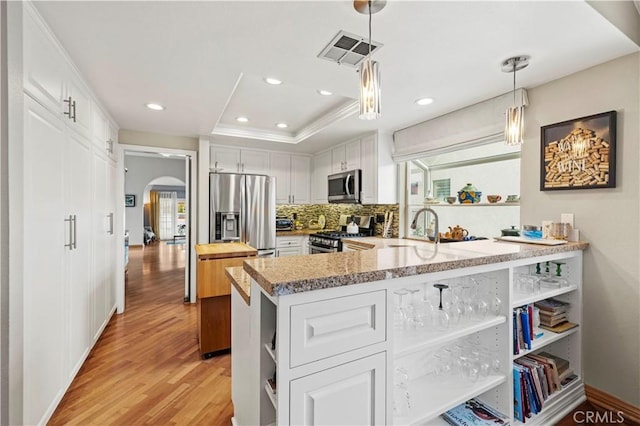 kitchen with white cabinets, stainless steel appliances, open shelves, visible vents, and arched walkways