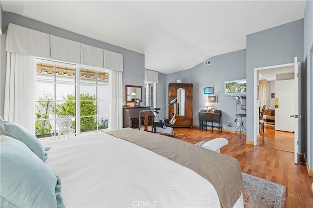 bedroom featuring wood finished floors, baseboards, vaulted ceiling, and visible vents