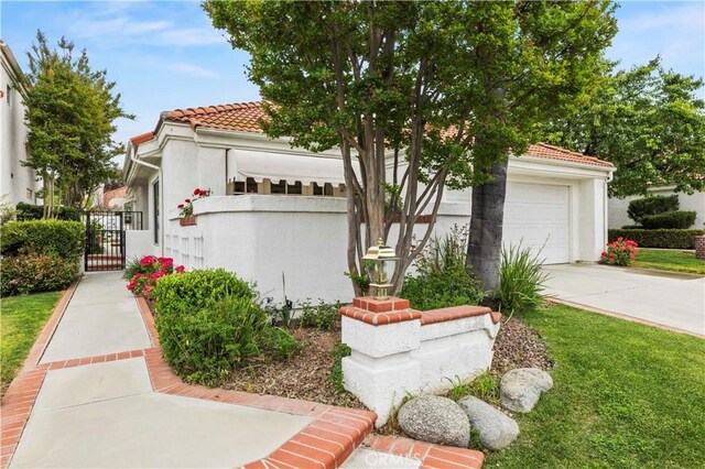 mediterranean / spanish home featuring a gate, a tile roof, concrete driveway, and stucco siding