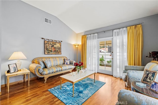 living room with high vaulted ceiling, wood finished floors, and visible vents