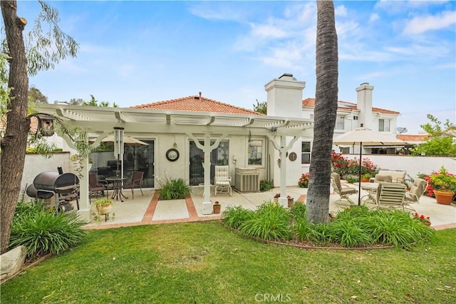 back of house featuring central AC, a tile roof, a pergola, a yard, and stucco siding