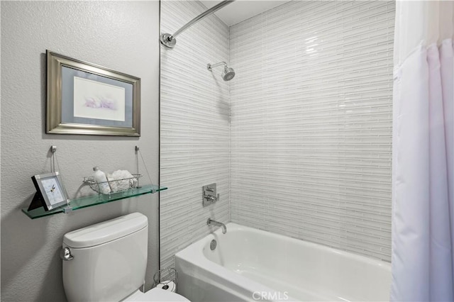 bathroom with shower / bath combo, toilet, and a textured wall