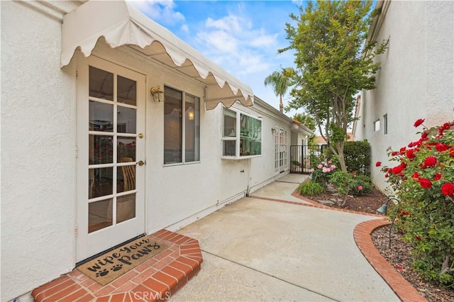 property entrance featuring a patio, stucco siding, and fence