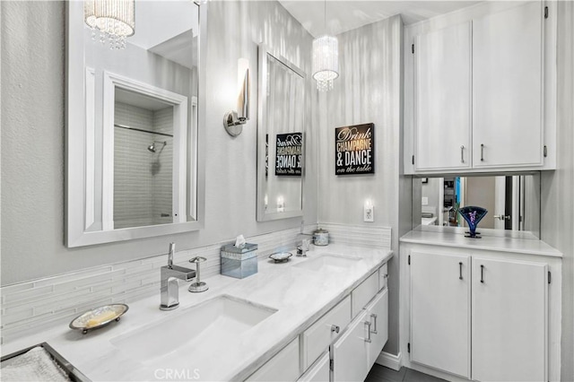 bathroom with an inviting chandelier, walk in shower, a sink, and double vanity