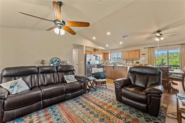 living area featuring a ceiling fan, visible vents, recessed lighting, wood finished floors, and lofted ceiling