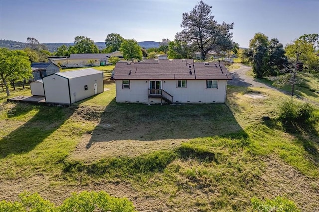 rear view of property featuring a yard, entry steps, an outbuilding, and crawl space