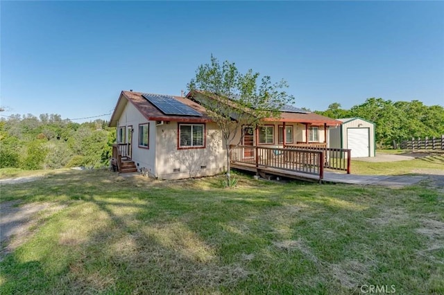 rear view of property featuring crawl space, an outbuilding, roof mounted solar panels, and a yard