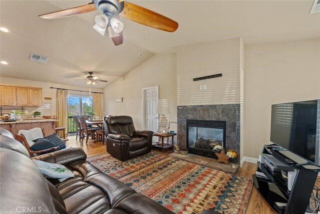 living room with visible vents, a ceiling fan, wood finished floors, and lofted ceiling