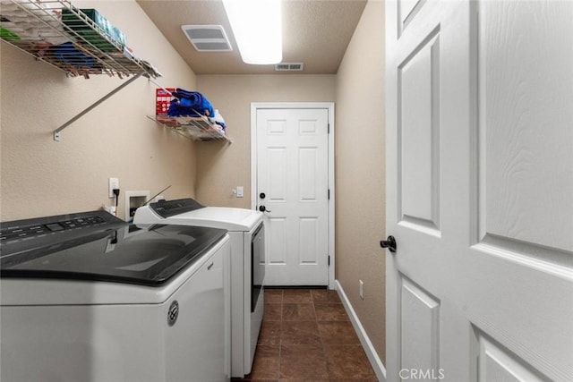 washroom featuring visible vents, baseboards, separate washer and dryer, dark tile patterned floors, and laundry area