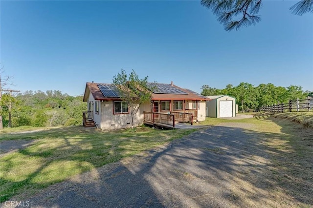 view of front of home with crawl space, solar panels, an outbuilding, a garage, and fence