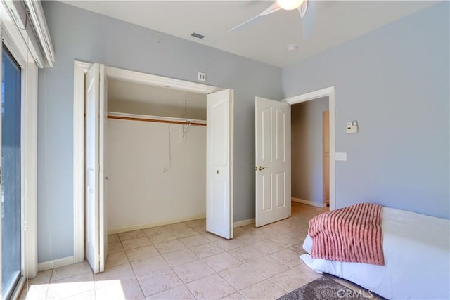 bedroom with a closet, baseboards, visible vents, a ceiling fan, and light tile patterned flooring